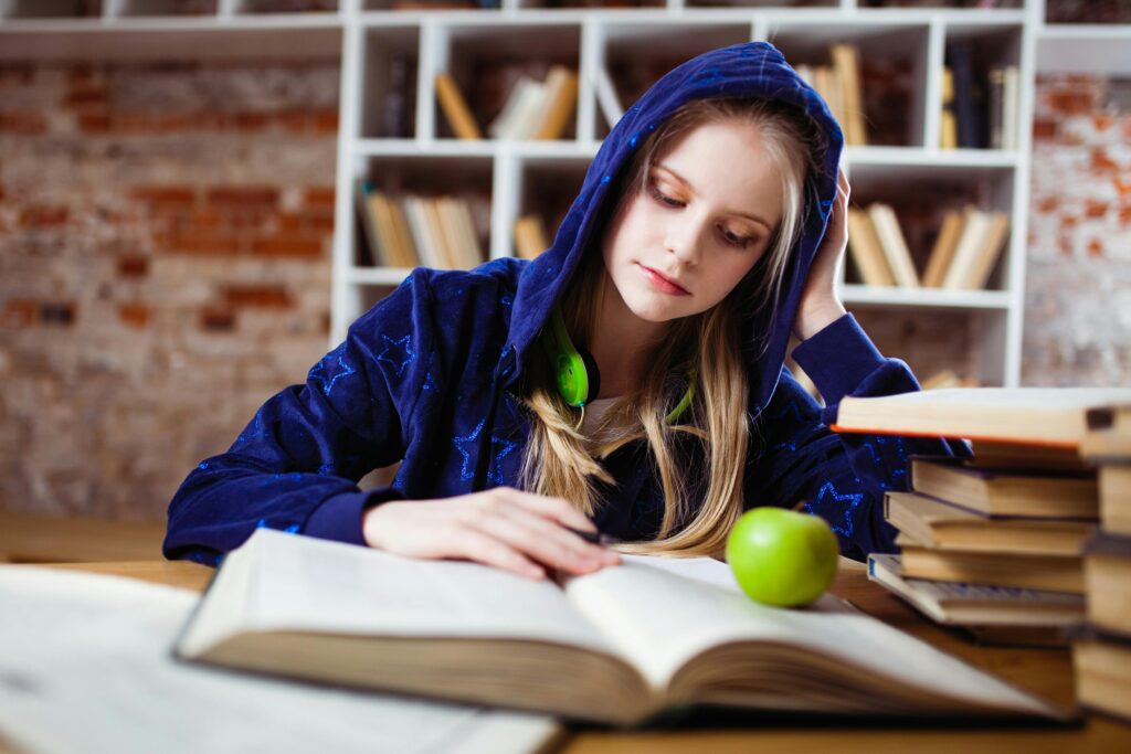 pexels-photo-1326947-1326947 Woman Wearing Blue Jacket Sitting on Chair Near Table Reading Books